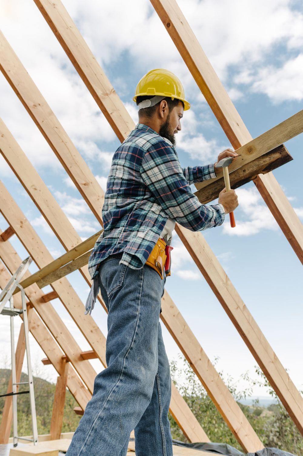 Trabajador con casco construyendo la estructura del techo de una casa